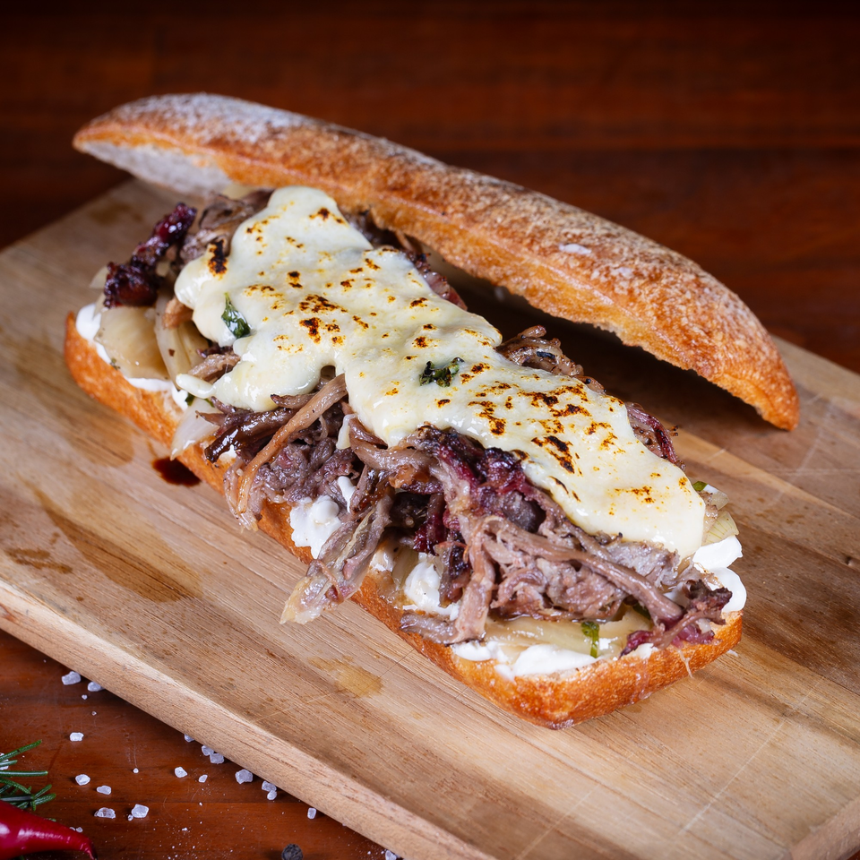 Patrick's Northshore Eatery's hearty sandwich with melted cheese, shredded meat, and onions on a baguette.