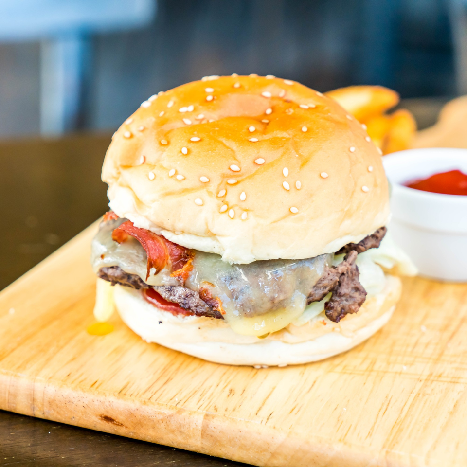 A Patrick's Northshore Eatery burger with bacon, melted cheese, and a side of ketchup.