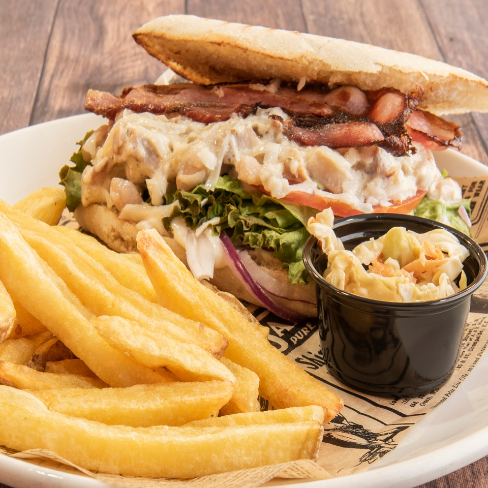 A Patrick's Northshore Eatery sandwich with bacon, lettuce, tomato, and onions, served with fries and coleslaw.