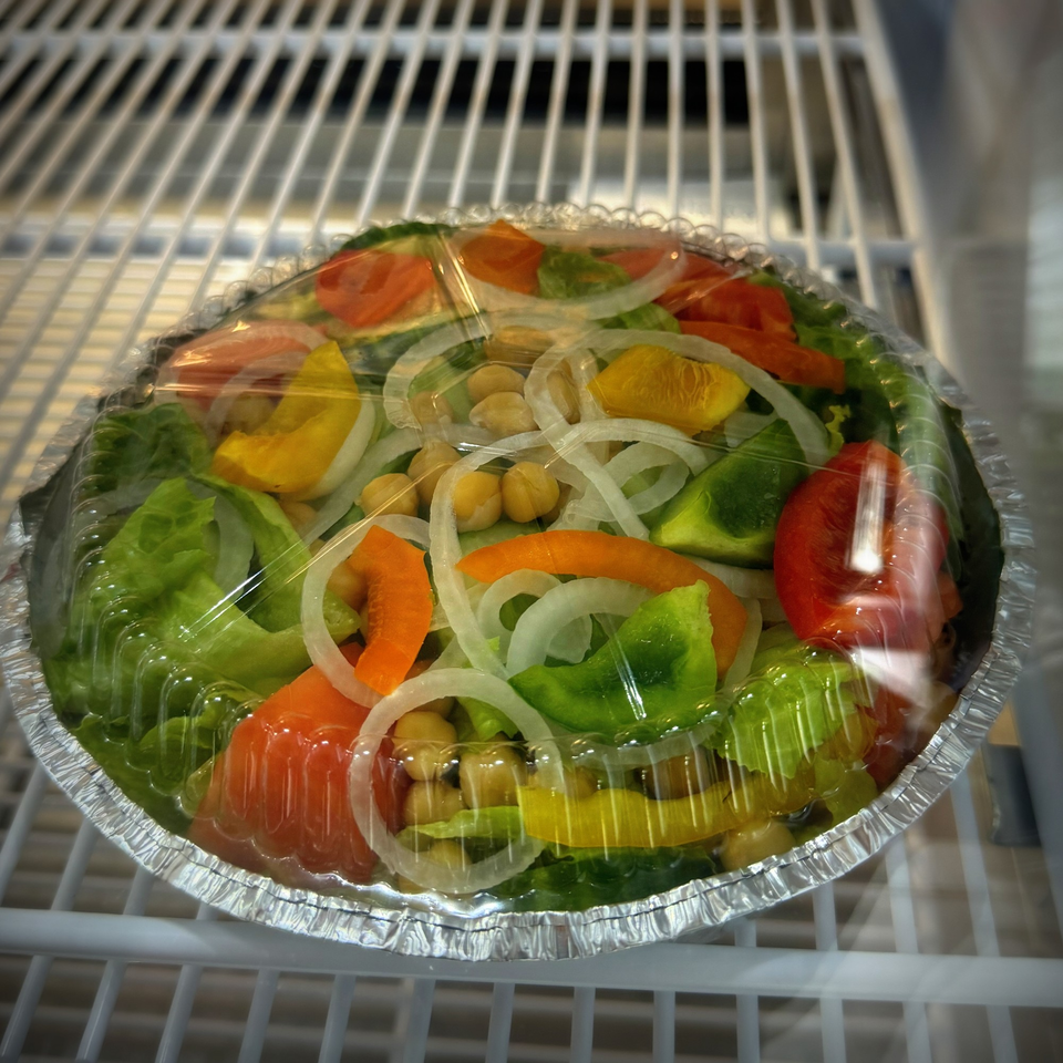 A fresh salad with lettuce, bell peppers, onions, and chickpeas in a foil container with a plastic lid.